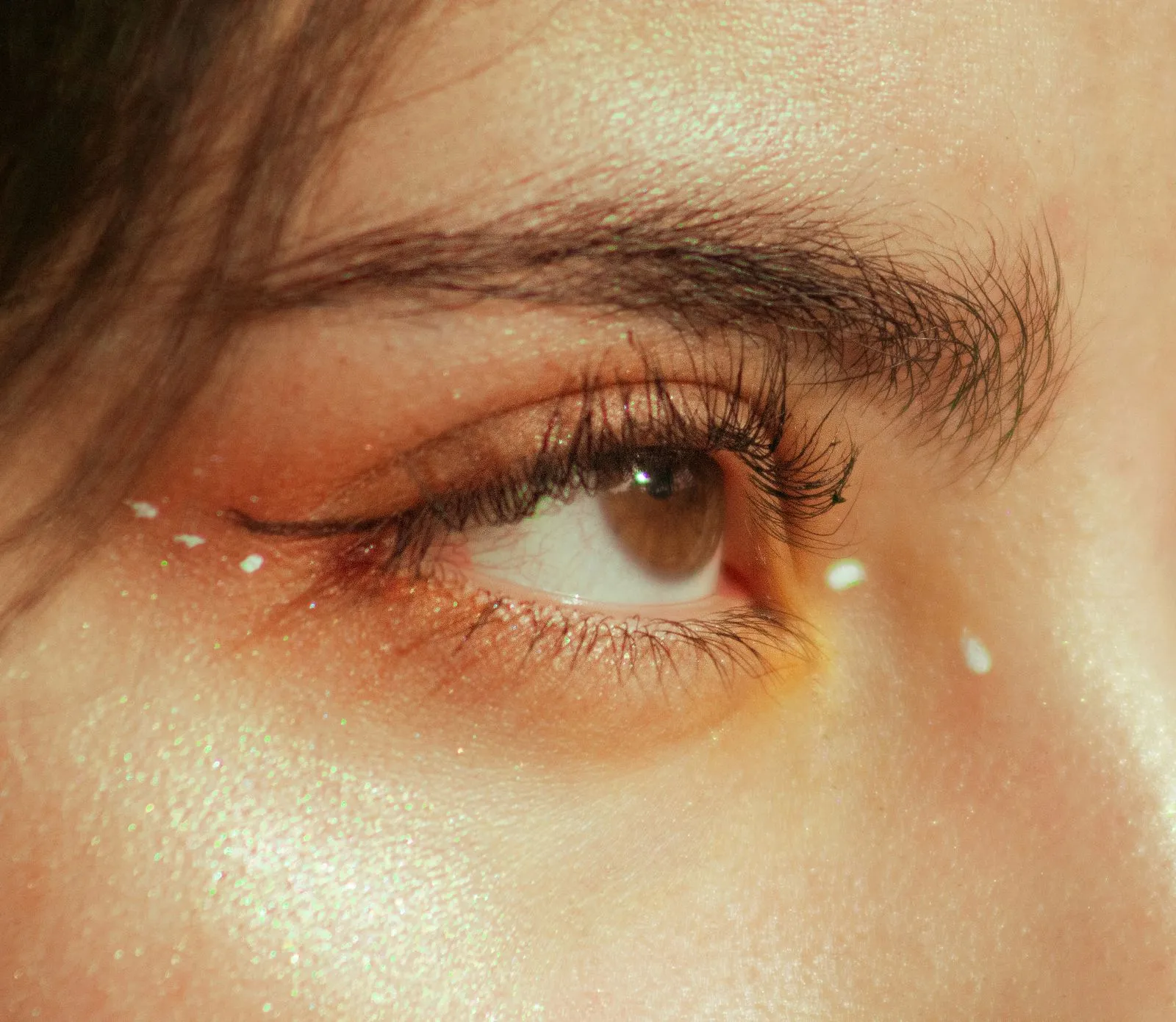 Detailed close-up of a woman's eye with shimmering makeup and artistic accents.